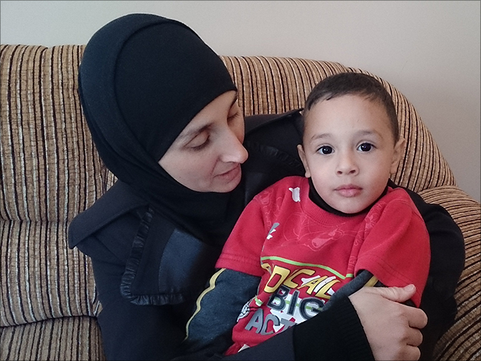 ‪زوجة الشهيد غسان أبو جمل مع ابنها الذي حاول مستوطنون اختطافه قبل أيام‬ (الجزيرة)