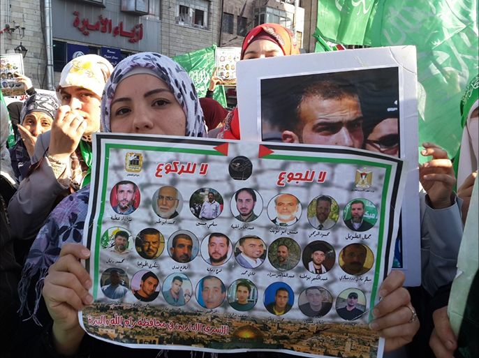 فلسطينية تحمل ملصقا للأسرى في فعالية لنصرتهم برام الله