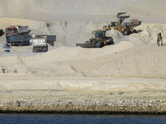 An Egyptian soldier stands guard as bulldozers and trucks work on a new section of the Suez Canal during a media tour in Ismailia, Egypt, Wednesday, Feb. 4, 2015. The head of the Suez Canal Authority, Mohab Mameesh, says work is on schedule and that so far, 86 percent of the dry digging and 21 percent of the dredging has been completed, with the new section expected to be completed in August 2015. . (AP Photo/Hassan Ammar)