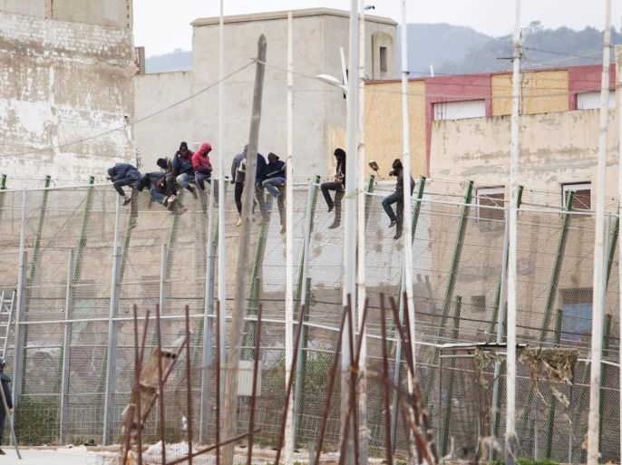 Would-be immigrants sit atop a border fence after attempting to cross from Morocco to the Spanish enclave of Melilla on February 10, 2015. More than 600 immigrants tried today to climb over the wire border fence with 35 making it to Mellila, said the prefecture of the enclave. AFP PHOTO/ ANGELA RIOS