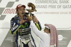Movistar Yamaha MotoGP rider Valentino Rossi of Italy celebrates with his trophy on the podium after winning the MotoGP race of the Qatar Grand Prix on March 29, 2015 at the Losail International Circuit in the Qatari capital Doha. AFP PHOTO / AL-WATAN DOHA / KARIM JAAFAR == QATAR OUT ==