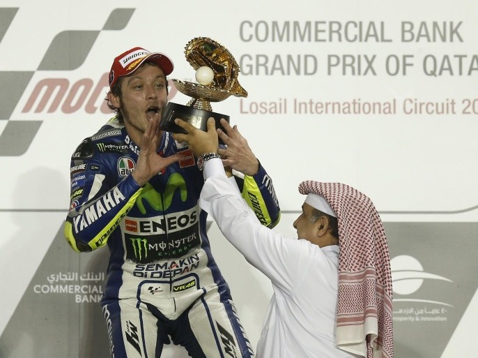 Movistar Yamaha MotoGP rider Valentino Rossi of Italy celebrates with his trophy on the podium after winning the MotoGP race of the Qatar Grand Prix on March 29, 2015 at the Losail International Circuit in the Qatari capital Doha. AFP PHOTO / AL-WATAN DOHA / KARIM JAAFAR == QATAR OUT ==
