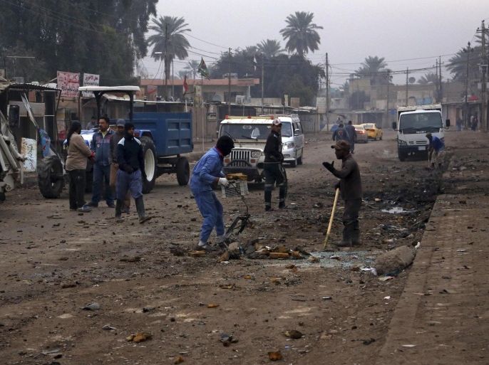 Municipality workers clean up debris in the aftermath of a car bomb explosion in Baghdad's southeastern suburb of Jisr Diyala, Iraq, Wednesday, Feb. 25, 2015. A series of bombings in Iraq, including twin blasts in a busy street in Jisr Diyala, killed tens of people and wounded dozens on Tuesday, Iraqi officials said. (AP Photo/Khalid Mohammed)