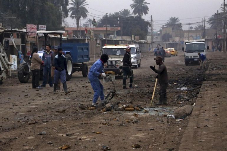 Municipality workers clean up debris in the aftermath of a car bomb explosion in Baghdad's southeastern suburb of Jisr Diyala, Iraq, Wednesday, Feb. 25, 2015. A series of bombings in Iraq, including twin blasts in a busy street in Jisr Diyala, killed tens of people and wounded dozens on Tuesday, Iraqi officials said. (AP Photo/Khalid Mohammed)