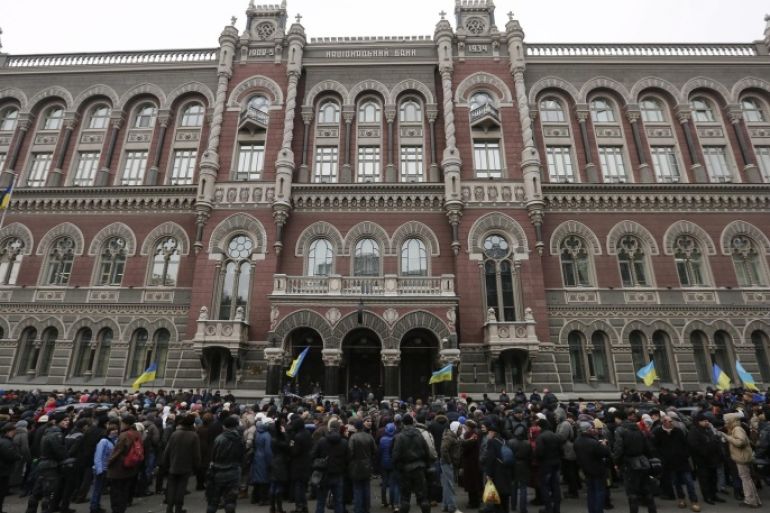 People attend a rally against the financial policy of the Ukrainian National Bank in front of the Ukrainian National Bank building in downtown Kiev, Ukraine, 24 February 2015. Ukraine's central bank introduced new capital controls in an attempt to stem a collapse of the country's currency, which has lost more than half of its value since the crisis that erupted in early 2014. Foreign ministers of Russia, Ukraine, France and Germany made a fresh call for a 'strict implementation' of the ceasefire agreement in eastern Ukraine and suggested expanding an international observer mission there.