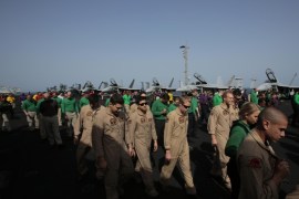 U.S. sailors and pilots walk on the flight deck, checking for any debris, aboard the USS Carl Vinson aircraft carrier in the Persian Gulf, Thursday, March 19, 2015. U.S. aircraft aboard the Carl Vinson as well as French military jets aboard the nearby French carrier Charles de Gaulle are flying missions over Iraq in the fight against Islamic State militants. (AP Photo/Hasan Jamali)