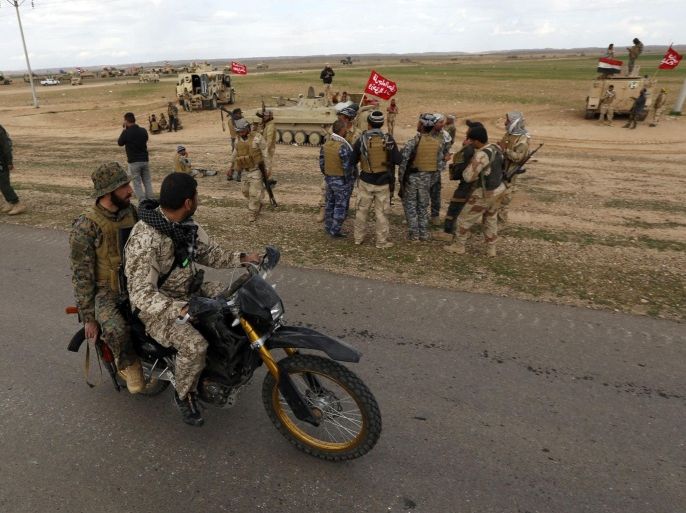 Shi'ite fighters ride a motorbike in the town of Hamrin, in Salahuddin province March 3, 2015. Wearing military fatigues and a white turban, Shi'ite cleric Sheikh Ahmed al-Rubaei gave an eve-of-battle address to Iran-backed fighters preparing to attack Islamic State militants in Tikrit, praising them for defending their faith and urging them to fight honourably. This week's multi-pronged attack is the biggest coordinated assault on the city since the radical Islamic State fighters seized it in June, and also the clearest example of how Tehran, rather than Washington, is now playing a more important role on the battlefield in a war that sees both Iran and the United States supporting the same side against a common foe. Picture taken March 3, 2015. To match Insight MIDEAST-CRISIS/IRAQ-FRONT REUTERS/Thaier Al-Sudani (IRAQ - Tags: POLITICS CIVIL UNREST CONFLICT)