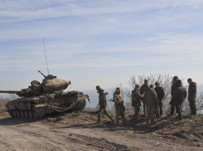 Ukraine government forces stand by a tank on a front line position east of the Sea of Azov port city, Mariupol, Ukraine, Tuesday, March 10, 2015. The bulk of continued unrest along the 485-kilometer (300-mile) front lines, between Ukraine's government forces and Russia-backed rebels, has been concentrated around the separatist stronghold of Donetsk, but pitched battles are also taking place in the town of Shyrokyne, near the strategic port city of Mariupol. (AP Photo/Vadim Ghirda)