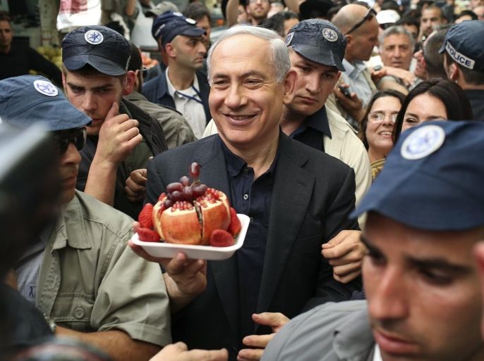 Israel's Prime Minister Benjamin Netanyahu (C) holds a plate of fruit during a visit to Mahane Yehuda market in Jerusalem in this March 9, 2015 file photo. Israel's Sephardic community, Jews of Middle Eastern descent, have traditionally been the Likud party's backbone. But political analysts say Sephardim, disproportionately poorer than Israel's Ashkenazi Jews with roots in Europe, may throw their support elsewhere in the March 17 election, angry over the high cost of living and housing prices. Netanyahu's battle to preserve Sephardic backing in Israel's lower-income areas is being played out in places such as Jerusalem's Mahane Yehuda market, where the prime minister himself made an appearance on Monday. REUTERS/Noam Moskowitz/Files (JERUSALEM - Tags: POLITICS FOOD ELECTIONS) ISRAEL OUT. NO COMMERCIAL OR EDITORIAL SALES IN ISRAEL