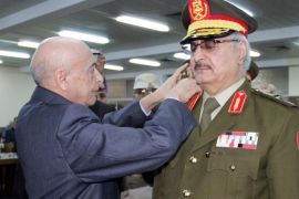An unidentified Libyan official adjusts a rank to the uniform of anti-Islamist General Khalifa Haftar (R) during his swearing in ceremony as the new army chief in conflict-ridden Libya on March 9, 215, in the eastern city of Tobruk. The once-retired general leading a sweeping offensive against Islamists has been sworn in head of the Libyan army loyal to the country's internationally recognised parliament, in a move expected to deepen divisions in the conflict-riven nation. AFP / STR