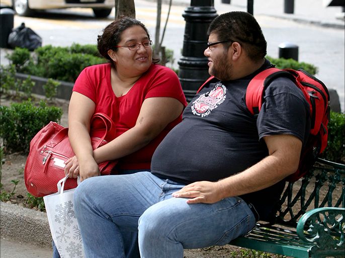 شخصان يعانان من السمنة المفرطة يجلسان على مقعد في مكسيكو سيتي. Credit: Jorge Rios Ponce / dpa
