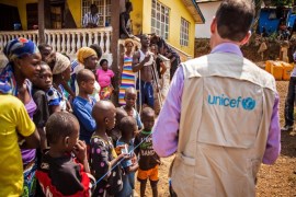 In this photo taken on Thursday, Feb. 26, 2015, A UNICEF aid worker, right, visits a home that has been quarantined due to Ebola virus for twenty one days in Freetown, Sierra Leone. Ten clinicians with a Boston-based nonprofit organization responding to the Ebola outbreak in Sierra Leone are to be transported to the United States after one of their colleagues was infected with the deadly disease. Partners in Health said in a statement Saturday, March 14, 2015, that the medical workers would be evacuated on non-commercial aircraft and isolated in Ebola treatment facilities. (AP Photo/ Michael Duff)