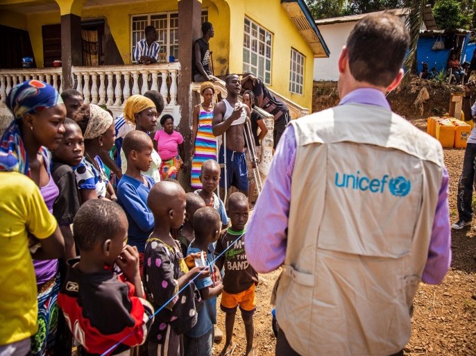 In this photo taken on Thursday, Feb. 26, 2015, A UNICEF aid worker, right, visits a home that has been quarantined due to Ebola virus for twenty one days in Freetown, Sierra Leone. Ten clinicians with a Boston-based nonprofit organization responding to the Ebola outbreak in Sierra Leone are to be transported to the United States after one of their colleagues was infected with the deadly disease. Partners in Health said in a statement Saturday, March 14, 2015, that the medical workers would be evacuated on non-commercial aircraft and isolated in Ebola treatment facilities. (AP Photo/ Michael Duff)