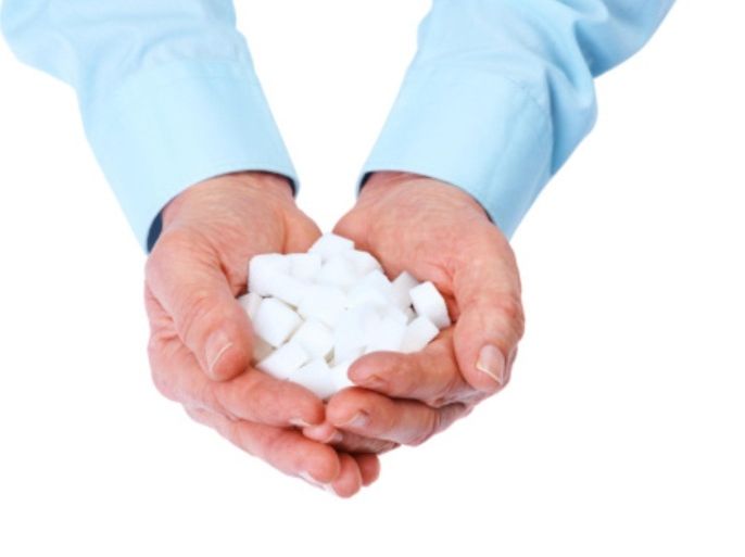 Closeup image of a cupped human hand with sugar cubes against white