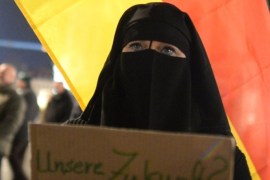 A veiled person holds a poster reading 'Our future, no thanks' in front of a German national flag, during a march of the socalled movement of Patriotic Europeans Against the Islamisation of the Occident aka Pegida, in Dresden, eastern Germany, on March 2, 2015. PEGIDA marches -- which have voiced anger against Islam and 'criminal asylum seekers' -- began with several hundred supporters in October 2014, drawing a record 25,000 people on January 12, 2015 just after the Paris Islamist attacks. AFP PHOTO / DPA / ARNO BURGI +++ GERMANY OUT