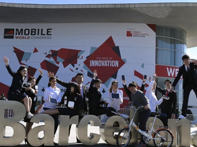 A group of MWC workers pose for a photo outside the 2014 Mobile World Congress in Barcelona on February 28, 2015. The 2015 Mobile World Congress, where participants can attend conferences and discover cutting-edge products and technologies, is the world's biggest mobile fair and will be held from March 2 to 5 in Barcelona. AFP PHOTO / LLUIS GENE