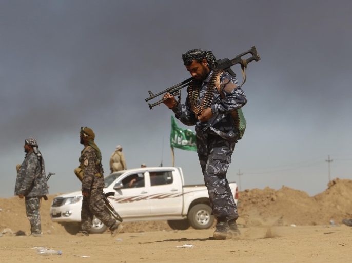 A Shi'ite fighter walks with his weapon in the town of Tal Ksaiba, near the town of al-Alam March 7, 2015. Iraqi security forces and Shi'ite militia fighters struggled to advance on Saturday into the two towns of al-Alam and al-Dour near Tikrit, their progress slowed by fierce defence from Islamic State militants. REUTERS/Thaier Al-Sudani (IRAQ - Tags: POLITICS CIVIL UNREST CONFLICT)