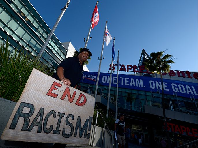 epa04185757 A fan holds a banner reading 'End Racism!' as he stands outside Staples Center prior to the Golden State Warriors at Los Angeles Clippers NBA Conference Quarterfinal game five playoff in Los Angeles, California, USA, 29 April 2014. Clippers owner Donald Sterling was banned for life and fined 2.5 million US dollar for racist comments he made to girlfriend who was audio taping the conversation. EPA/PAUL BUCK CORBIS OUT