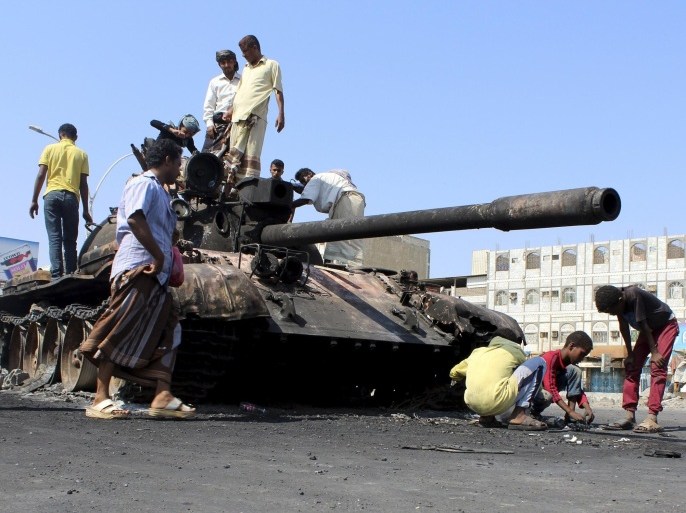 People gather near a tank burnt during clashes on a street in Yemen's southern port city of Aden March 29, 2015. Yemeni fighters loyal to the Saudi-backed President Abd-Rabbu Mansour Hadi clashed with Iranian-allied Houthi fighters on Sunday in downtown Aden, the absent leader's last major foothold in the country. REUTERS/Stringer