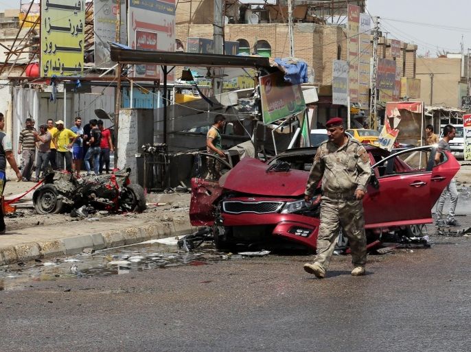 Civilians and security forces gather at the scene of a car bomb explosion in Talibiya in eastern Baghdad, Iraq, Wednesday, April 22, 2015. Two bomb blasts in Baghdad killed and wounded civilians, officials said. (AP Photo/Khalid Mohammed)