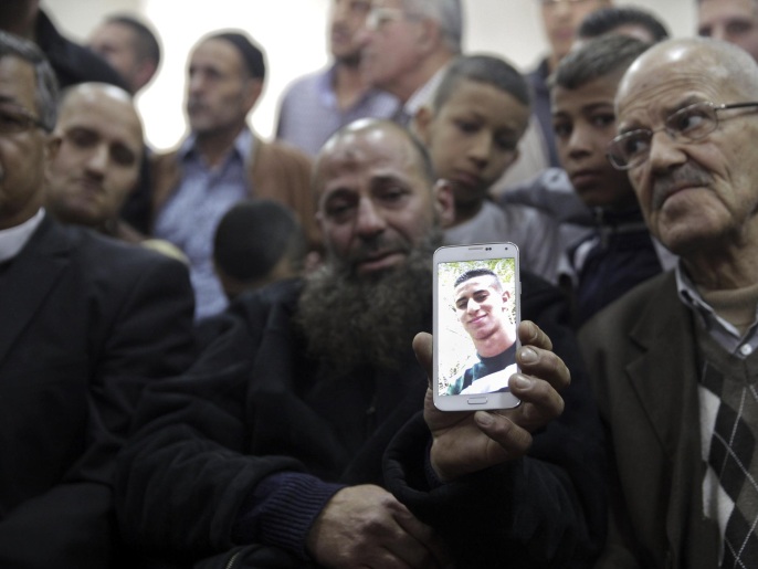 والد علي أبو غنام يحمل صورة ابنه الشهيد على هاتفه النقال (أسوشيتد برس)