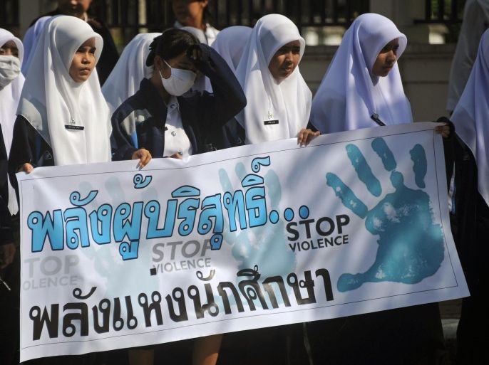 Thai Muslim students hold an anti-violence campaign placard as they parade in Thailand's restive southern province of Narathiwat on November 11, 2014. A grinding conflict has claimed more than 6,000 lives in a decade across the kingdom's Muslim-majority southernmost provinces, where shadowy rebels are fighting for a level of autonomy from the Thai state. AFP PHOTO / MADAREE TOHLALA