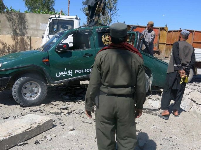 Members of the Afghan security forces inspect the site of a roadside bomb blast that targeted a police vehicle in Kandahar, Afghanistan, 12 April 2015. According to local reports at least three policemen were killed in a roadside bomb blast in Kandahar on 12 April.
