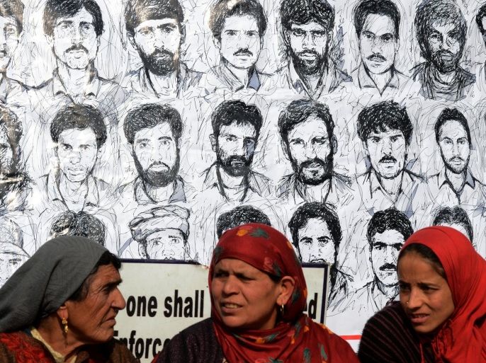 Kashmiri members of the Association of Parents of the Disappeared (APDP) take part in a protest in front of a banner depicting those missing on International Human Rights Day in Srinagar on December 10, 2014. Indian forces in Kashmir are often blamed for grave rights abuses like widespread torture, rape, custodial murder and enforced disappearences in the Muslim-majority region which is divided and administered separately by India and Pakistan but claimed in full by both. AFP PHOTO/Tauseef MUSTAFA