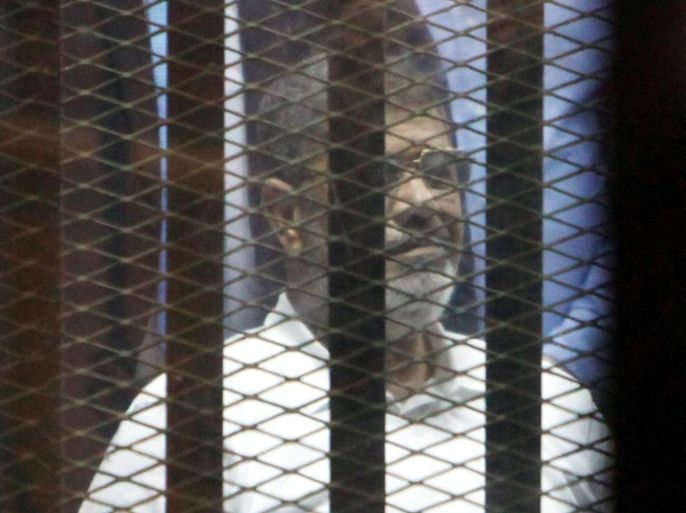 Ousted Egyptian president Mohammed Morsi looks from behind dock bars during trial session, in Cairo, Egypt, 21 April 2015. An Egyptian court sentenced ousted president Mohammed Morsi and 12 other Muslim Brotherhood leaders and officials to 20 years in prison over the killing of protesters during a 2012 demonstration outside the presidential palace in Cairo.