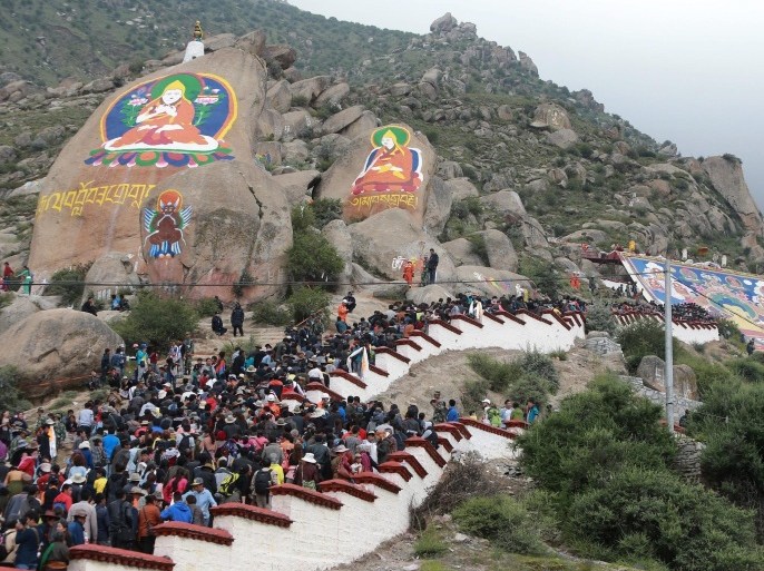 Pilgrims and tourists gather to view a giant thanka of a religious Sakyamuni Buddha painting after its unveiling on a hill to celebrate the Sho Dun Festival at Drepung monastery in Lhasa city, western China's Tibet Autonomous Region, 25 August 2014. The event, which is most important traditional festival in Tibet, runs from 25 August to 02 September and sees Tibetan people pray to giant thanka of religious Sakyamuni Buddha paintings in monasteries, drink yogurt, watch opera and enjoy entertainment of folk songs and dances.