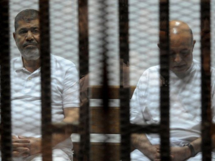 Egypt's deposed Islamist president Mohamed Morsi (L) and former presidential chief of staff Rafaa el-Tahtawi, sit inside the defendants cage during his trial at the police academy in Cairo on October 14, 2014. Morsi is on trial in several cases and faces a death sentence if convicted of espionage and terrorism related charges. AFP PHOTO / STR