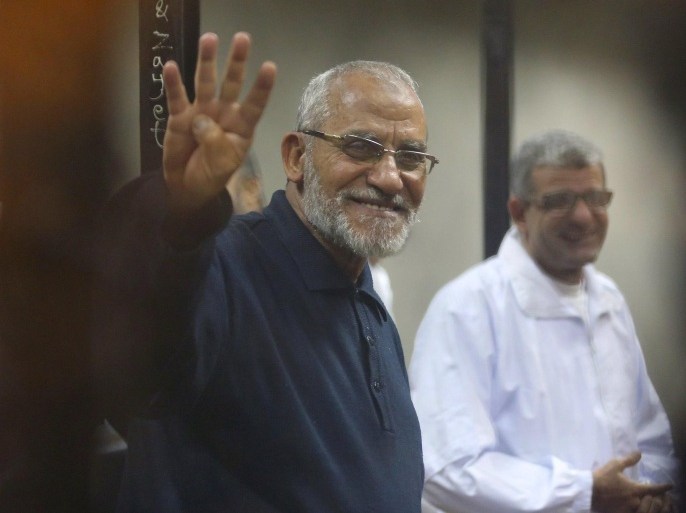 Muslim Brotherhood's Supreme Guide Mohamed Badie (L) flashes the Rabaa sign as he stands behind bars during his trial with ousted Egyptian President Mohamed Mursi and other leaders of the brotherhood at a court in the police academy on the outskirts of Cairo in this December 14, 2014 file photo. An Egyptian court on April 11, 2015 sentenced Badie, leader of the outlawed Muslim Brotherhood, and 13 other senior members of the group to death for inciting chaos and violence, and gave a life term to a U.S.-Egyptian citizen for ties to the Brotherhood. REUTERS/Asmaa Waguih/Files (EGYPT - Tags: POLITICS CRIME LAW CIVIL UNREST)