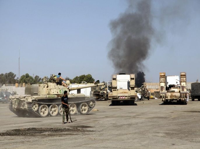 Smoke is seen rising from the Brigade Qaqaa headquarters, a former Libyan Army camp known as Camp 7 April, behind members of the Libya Shield, following clashes between rival militias at the Sawani road district in Tripoli, August 24, 2014. REUTERS/Stringer (LIBYA - Tags: POLITICS CIVIL UNREST)