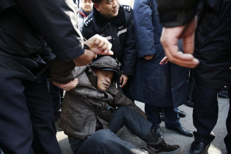 A family member of a passenger onboard the missing Malaysia Airlines flight MH370, is stopped by policemen as he tries to approach the Malaysian Embassy during a protest demanding the Malaysian government to keep searching the missing flight, in Beijing January 29, 2015. Malaysia's Department of Civil Aviation will release an interim report on the investigation into the missing Malaysia Airlines Flight MH370 on March 7, a day before the one-year anniversary of the disappearance, deputy transport minister Aziz Kaprawi said on Wednesday.REUTERS/Kim Kyung-Hoon (CHINA - Tags: DISASTER TRANSPORT CIVIL UNREST)