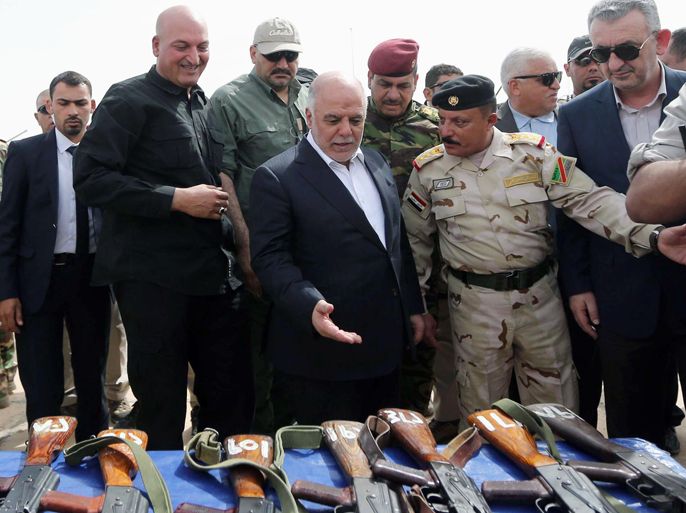 In this photo taken on Wednesday, April 8, 2015 Iraqi Prime Minister Haider al-Abadi, center, inspects weapons submitted to security forces and Sunni volunteers at a camp in Habaniyah, 80 kilometers (50 miles) west of Baghdad, Iraq. After victory against Islamic State militants in the city of Tikrit, Iraq's prime minister vowed, earlier in the week, to protect the people living in territories controlled by the Islamic State group from any retribution or rights violations when their lands are retaken by government forces. (AP Photo)
