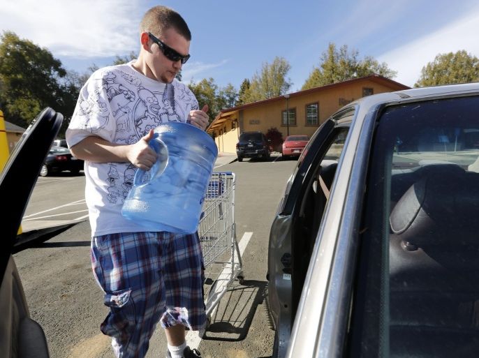 FILE - In this Feb. 4, 2014 file photo, Forrest Clark loads five-gallon bottles of water purchased at a local store into his car in Willits, Calif. State public health officials have reduced the number of communities at risk of losing their drinking water due to California's drought from 17 to three. In the Mendocino County town of Willits, which was two months from losing its drinking water, well drilling efforts and rain have helped officials ease restrictions. (AP Photo/Rich Pedroncelli, file)
