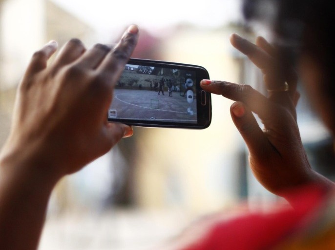 A woman uses her smartphone camera function to record a basketball game in Dakar, Senegal, on Sunday, Jan. 11, 2015. Dakar, with 3 million residents according to the CIA Factbook, is Senegal's largest city, economic hub and the business gateway to West Africa.