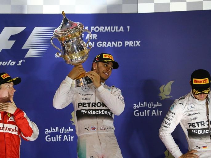 Mercedes AMG Petronas British driver Lewis Hamilton (C) hold his winners trophy as he stands on the podium after winning the Formula One Bahrain Grand Prix, ahead of Scuderia Ferrari Finnish driver Kimi Raikkonen (L) in second place and Mercedes AMG Petronas German driver Nico Rosberg (R) in third at the Sakhir circuit in the desert south of the Bahraini capital, Manama, on April 19, 2015. AFP PHOTO / MARWAN NAAMANI