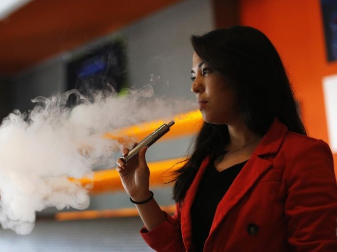 Enthusiast Brandy Tseu uses an electronic cigarette at The Vapor Spot vapor bar in Los Angeles, California in this March 4, 2014 file photograph. E-cigarettes, metal tubes that heat liquids typically laced with nicotine and deliver vapor when sucked, are transforming the market for smoking cessation products and slowing the $2.4 billion in global sales of long-standing aids such as nicotine patches and gums. But their impact on health remains unclear, experts say, raising difficult questions for regulators who are starting to impose limits on e-cigarette use. To match Feature HEALTH-ECIGARETTES/QUITTING REUTERS/Mario Anzuoni/Files (UNITED STATES - Tags: POLITICS SOCIETY HEALTH)