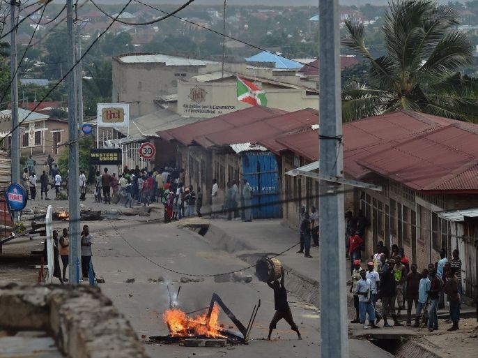 A Protestor opposed to the Burundian President's third term throws material onto a burning barricade in the Kinanira neighborhood of Bujumbura on May 21, 2015. At least two protesters were shot dead and eight were wounded today in clashes with police in the capital Bujumbura, the Red Cross said, the latest victims of the unrest triggered by President Pierre Nkurunziza's bid for a third term, in which more than 20 people have died. AFP PHOTO/Carl de Souza