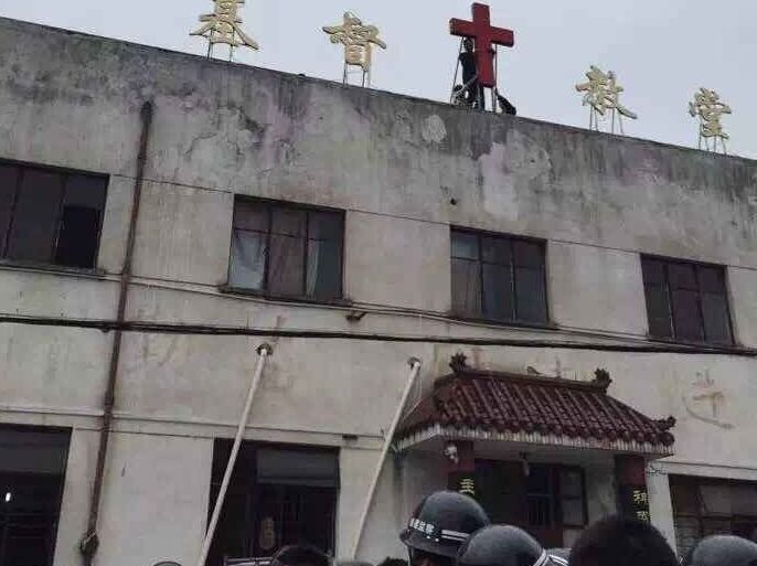 صينيون مسيحيون يتظاهرون برفع الصليب فوق كنيسة بعد قيام السلطات بإزالته