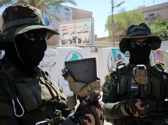 fighters of the Shiite militia Asaib Ahl al-Haq (The League of the Righteous) stand guard outside their headquarters on May 18, 2015 in the Iraqi mainly Shiite southern city of Basra, as Shiite militias converged on Ramadi in a bid to recapture it from jihadists who dealt the Iraqi government a stinging blow by overrunning the city in a deadly three-day blitz. "When it comes to readiness, we have more than 3,000 fighters waiting for a signal from the secretary general (of Asaib) Sheikh Qais al-Khazali," spokesman Jawad al-Talabawi said. AFP PHOTO / HAIDAR MOHAMMED ALI