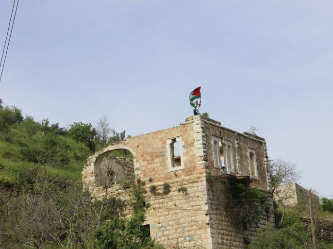 1-صورة من قرية لفتا المقدسية المهجرة عام 1948 وفتى فلسطيني يرفع العلم الفلسطيني فوق