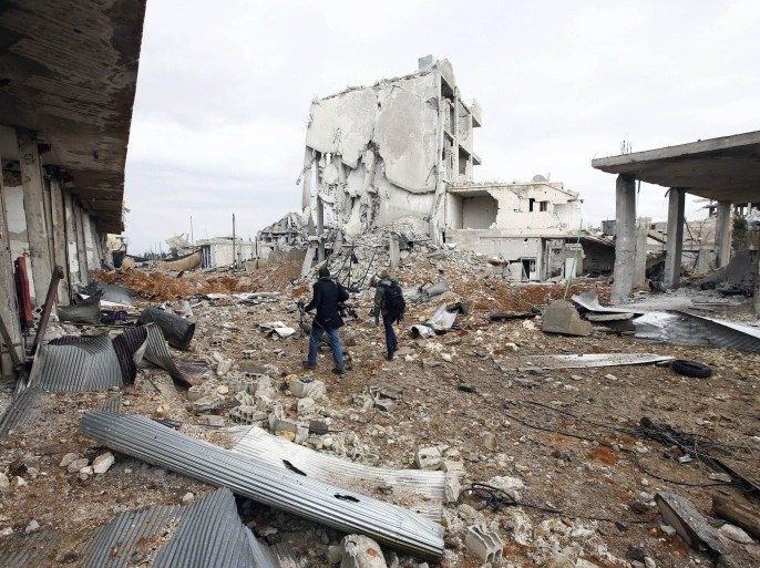Visiting journalists walk between damaged buildings in the northern Syrian town of Kobani January 30, 2015. Sheets meant to hide residents from snipers' sights still hang over streets in the Syrian border town of Kobani, and its shattered buildings and cratered roads suggest those who fled are unlikely to return soon. Kurdish forces said this week they had taken full control of Kobani, a mainly Kurdish town near the Turkish border, after months of bombardment by Islamic State, an al Qaeda offshoot that has spread across Syria and Iraq. REUTERS/Osman Orsal (SYRIA - Tags: POLITICS CONFLICT)