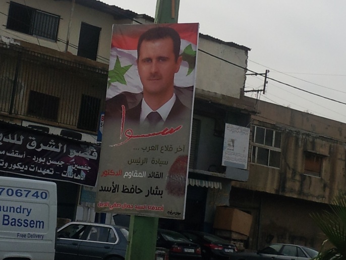 إحدى لافتات الدعم للأسد بمنطقة الآوزاعي المحسوبة على حزب الله (الجزيرة)