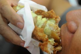 A man eats a 'Double Down Dog,' in Manila on February 3, 2015, a product conceived and introduced by the Philippine franchise of KFC. Fastfood giant KFC in the Philippines has begin selling a hotdog wrapped in fried chicken instead of bread and covered in cheese sauce to the horror of dieticians and amusement of social media users. AFP PHOTO / Jay DIRECTO