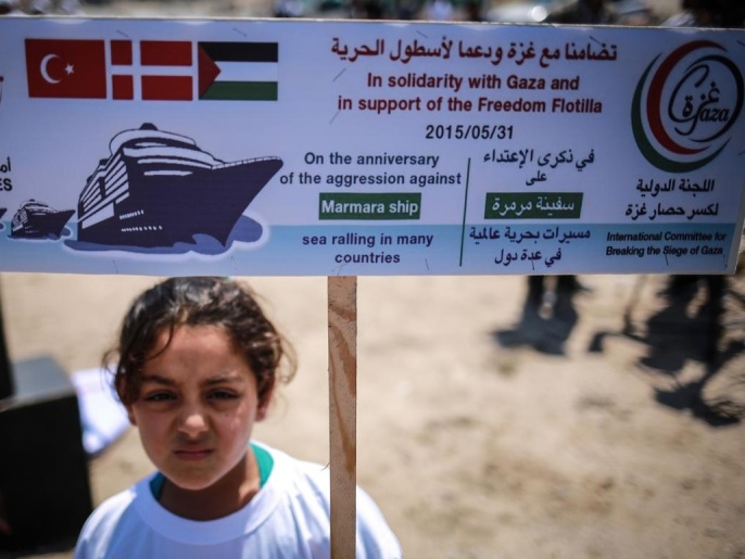 طفلة فلسطينية تحمل لوحة للتضامن مع غزة في ذكرى الهجوم على سفينة مرمرة (الأناضول)