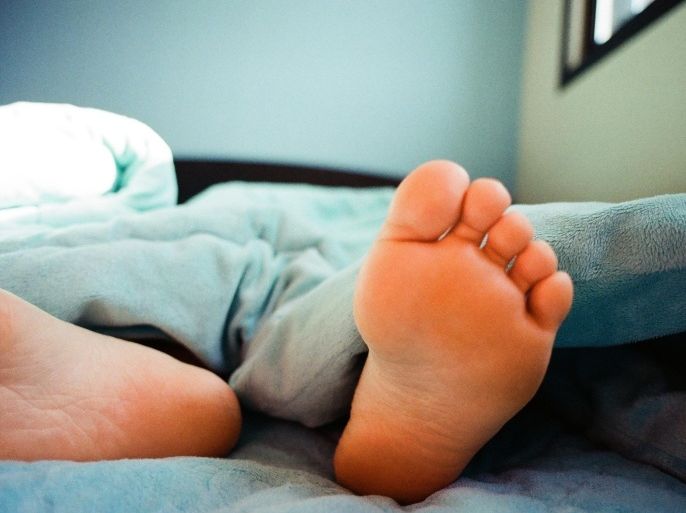 Low Section Of Person Sleeping On Bed