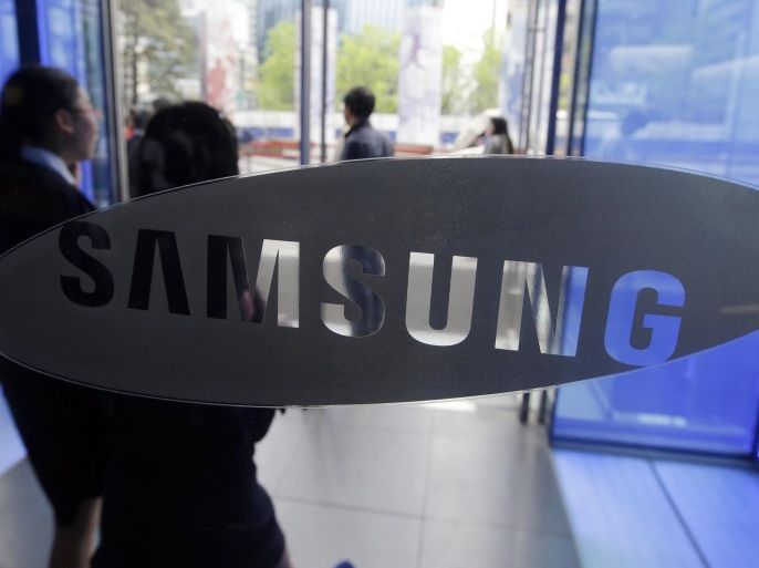 FILE - In this April 29, 2015 file photo, visitors walk by the logo of Samsung Electronics Co. at its showroom in Seoul, South Korea. Samsung wants to sell the digital brains that will go into billions of "smart" home appliances, industrial products and other Internet-connected gadgets — whether those gadgets are made by Samsung or its competitors. (AP Photo/Lee Jin-man, File)