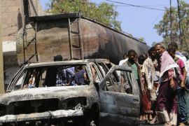 People look at a vehicle burned out after a truck behind it was hit by crossfire between fighters loyal to the exiled President Abed Rabbo Mansour Hadi and Shiite rebels and caused a fire in Taiz city, Yemen, Monday, May 25, 2015. Military officials said over 10 civilians died and some 200 others were wounded after the truck carrying oil was hit by crossfire and caused a raging fire. (AP Photo/Abdulnasser Alseddik)
